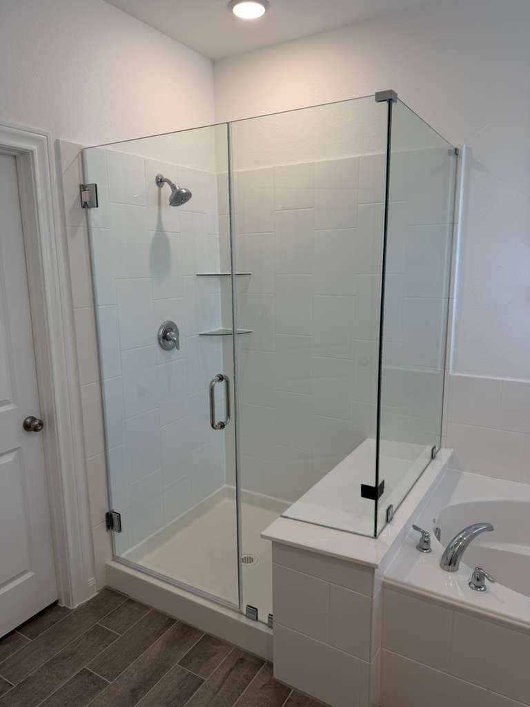 Frameless white-tile shower enclosure alongside soaking tub