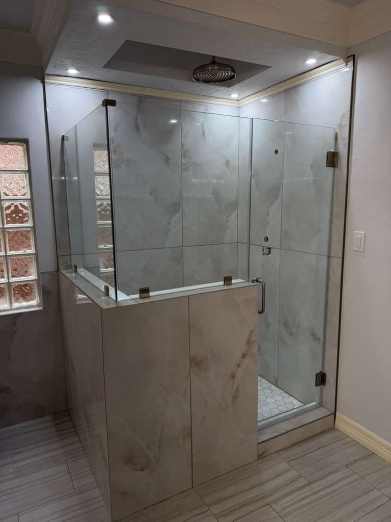 Frameless glass shower with knee wall and marble tile