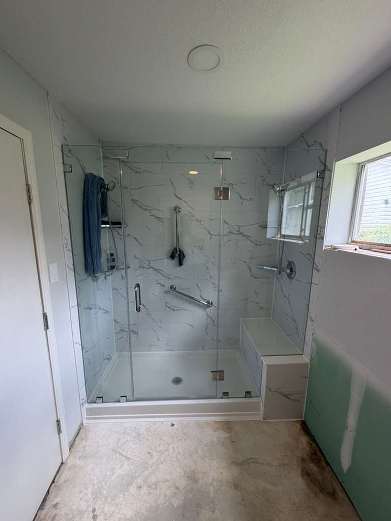Frameless glass shower enclosure with marble tile and built-in bench