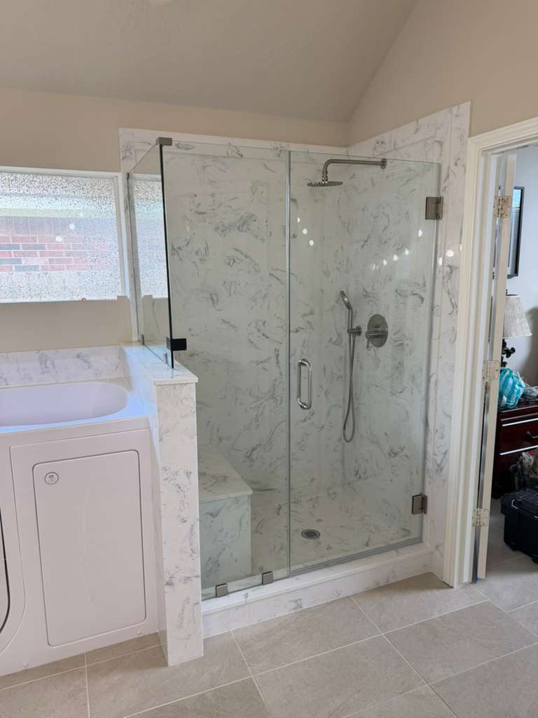 Frameless shower door with marble panels and brushed nickel fixtures